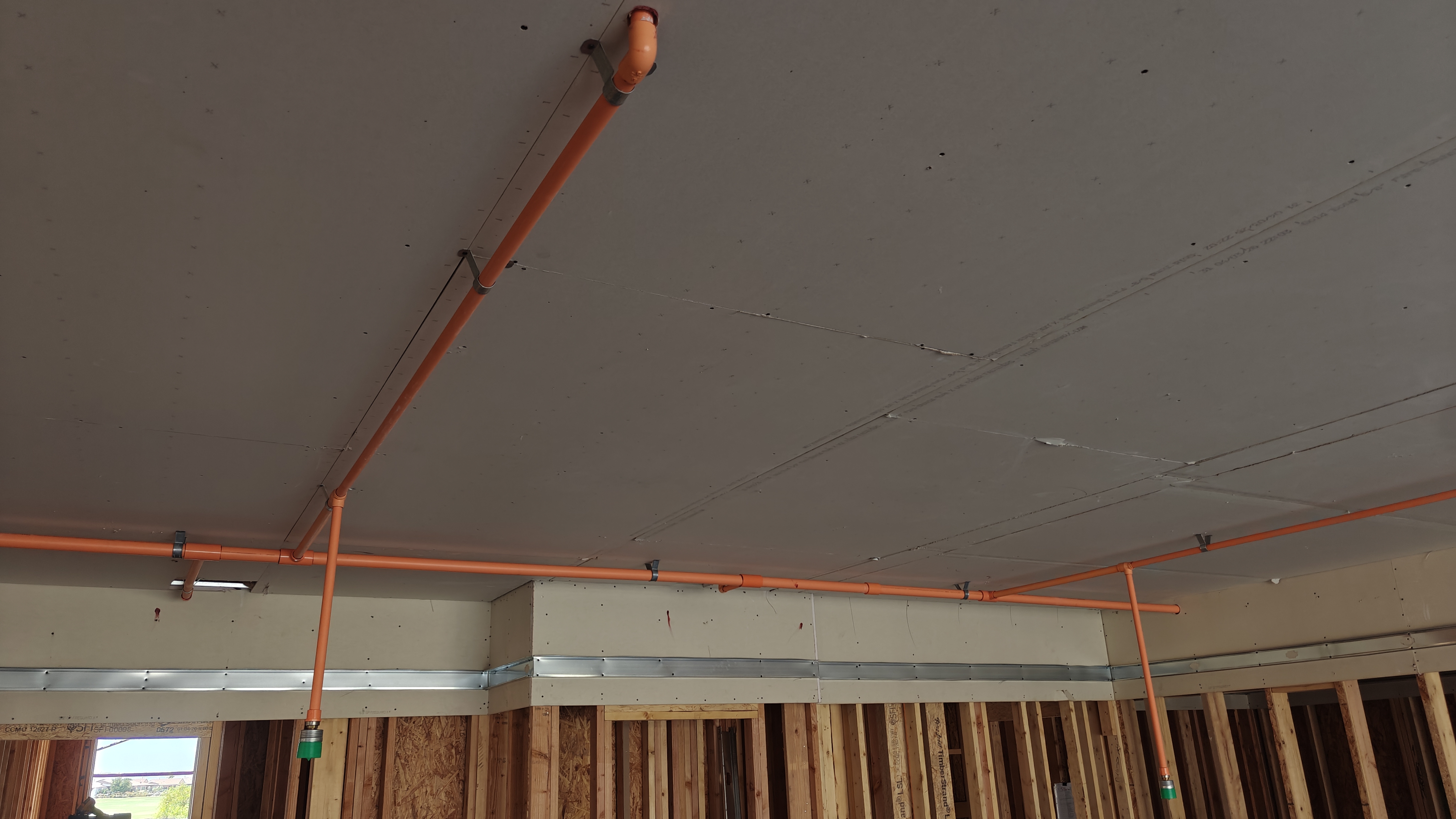 Close-up of orange fire protection piping, valve handle, and connected control component