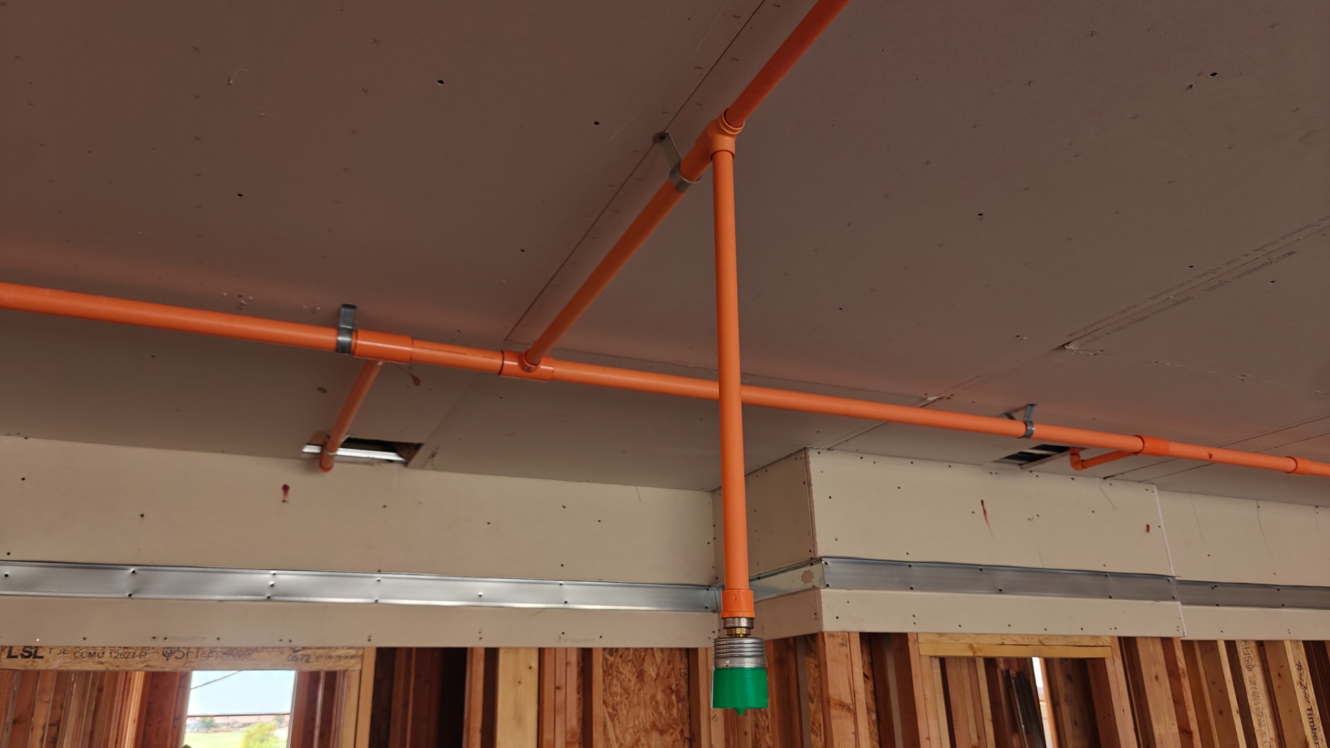 Orange CPVC fire sprinkler pipe run along commercial ceiling
